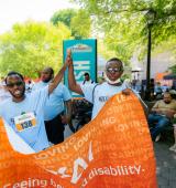 Diogeneis and a friend high-five each other while holding the CPC banner at the Central Park Challenge
