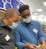 Portrait of Shakar Hollins (left) with a colleague (right) at CVS they are wearing disposable face masks and looking at an item