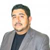 Headshot of Joshua Trinidad, he wears a grey suit jacket and black top