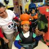 Jabir is in a wheelchair wearing an orange hat. Anitha is stood behind looking on.