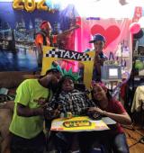 Family gathers together around iHOPE student, they have NYC taxi memorabilia and appear to be celebratory as they pose for the photo