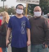 Vincent and his father are standing in a crowd wearing masks.