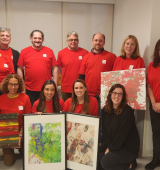 Group of McGraw Hill volunteers post with Megan holding some art pieces