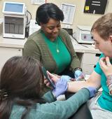 Patient at Premier HealthCare getting blood drawn with a nurse and OT supporting him.