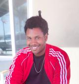 Headshot of Leonard, a black man with a great smile, wearing a red tracksuit top and black tshirt 