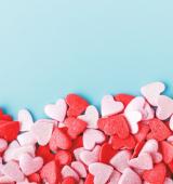 Red, pink, and white candy hears on a light blue background