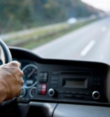 view from inside a car on the passenger side of a person driving a car on a long stretch of road