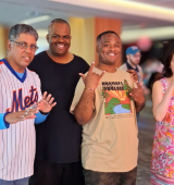 Kenneth with 3 other people standing together at the Summer Cookout Party, they are smiling and waving toward the camera