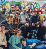 Large group of people pose in front of a colorful mural