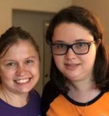 two women stand next to one another and smile for photo