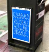A sign that says "disabled voters will be heard" on the road in New York City