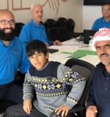 four men and a child sit around a table and look at the camera