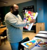 Jimmy Tucker, YAI artist, preps one of his pieces for delivery at the YAI Arts studio while practicing social distancing