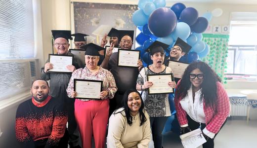 Group of people celebrating graduation from therapy, they are wearing mortars and holding certificates