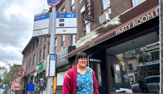 Lily stands at a bus stop in Brooklyn