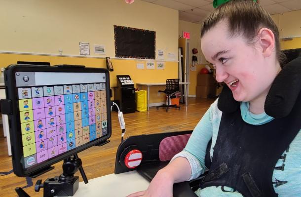 ihope student in a supportive wheelchair is interacting with screen of images and words to communicate