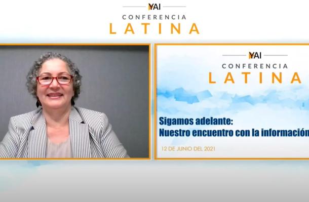 Screenshot of virtual Latino Conference, screen on left you see a woman with glasses and grey blazer, on right is a view of a powerpoint presentation