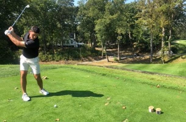 Person in mid-swing playing golf