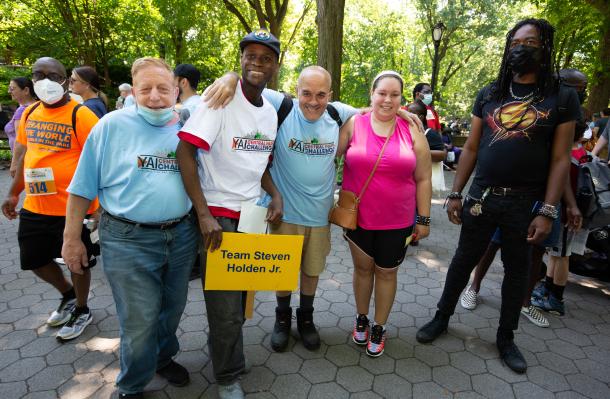 A group of people stand together in a row outside in the park for the central park challenge