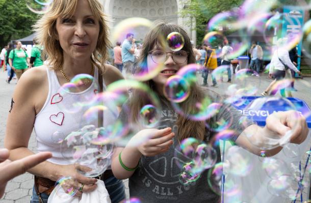 People stand by the bandshell in NY's Central Park. There are bubbles in front of them, so many bubbles.