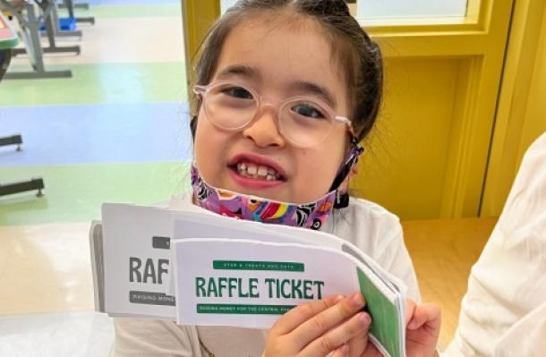 MSA student wearing glasses holds up raffle tickets