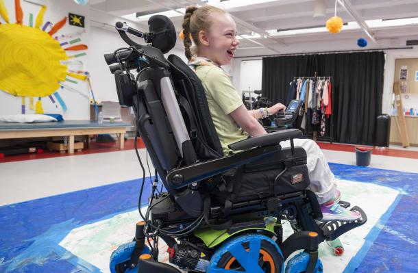 iHOPE student in a wheelchair creates art using the chair wheels. She has a very big smile on her face