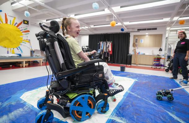 iHOPE student is creating art using her wheelchair, she has a big smile on her face