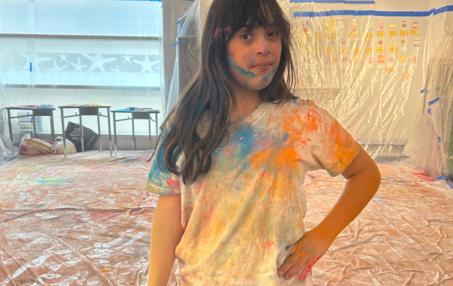 MSA student poses for camera, they are covered in colorful powder