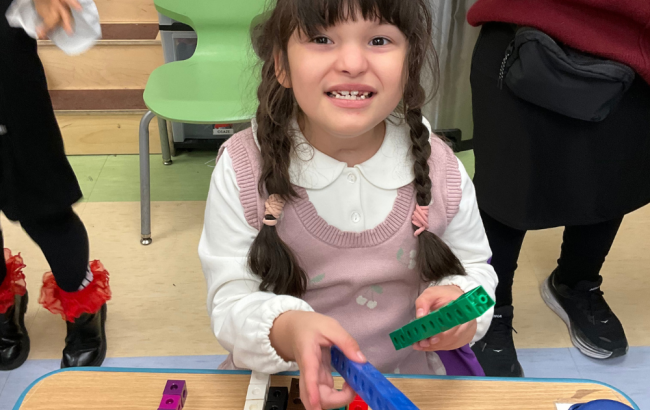 MSA student smiles as they hold counting pieces