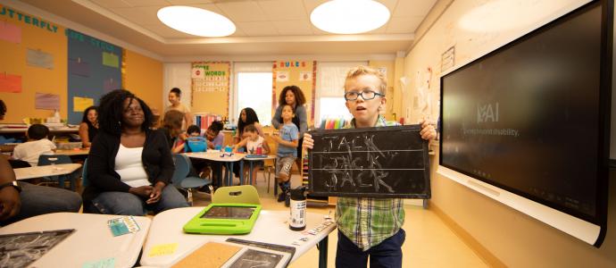 Manhattan Star Academy student stands in classroom holding a chalkboard with "Jack" written on it