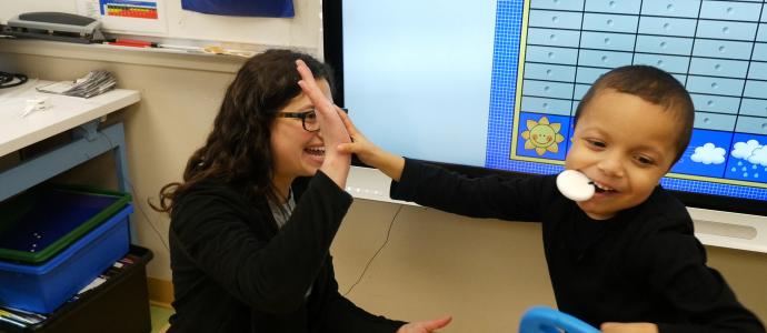 Adult and child giving a high five. They are in a school setting