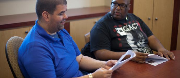 2 self advocates sit at a conference table to discuss the next issue