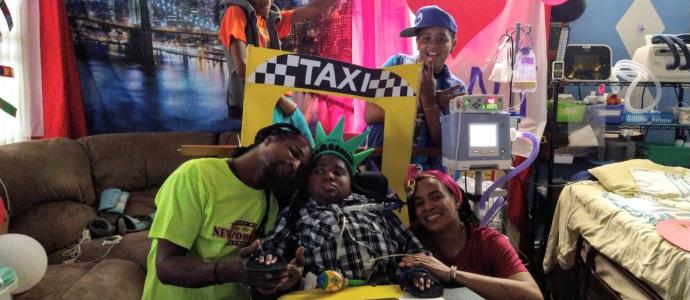 Family gathers together around iHOPE student, they have NYC taxi memorabilia and appear to be celebratory as they pose for the photo