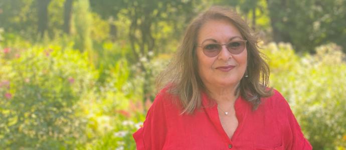 Person in red button-down shirt and sunglasses stands in front of a natural green space