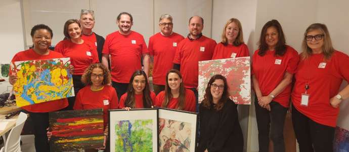 Group of McGraw Hill volunteers post with Megan holding some art pieces