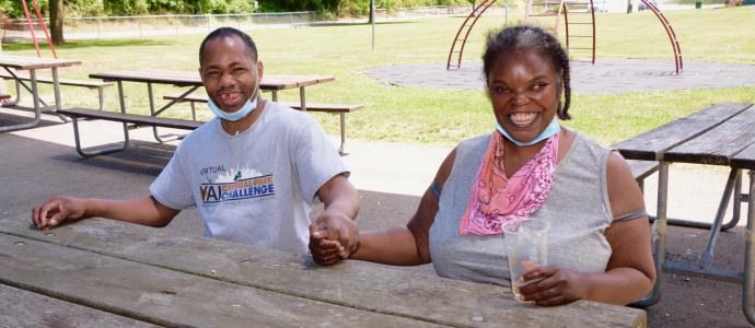 A couple sit together at a park, they are holding hands and smiling