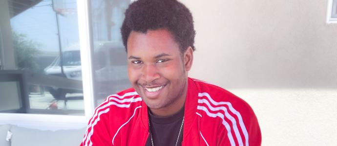 Headshot of Leonard, a black man with a great smile, wearing a red tracksuit top and black tshirt 