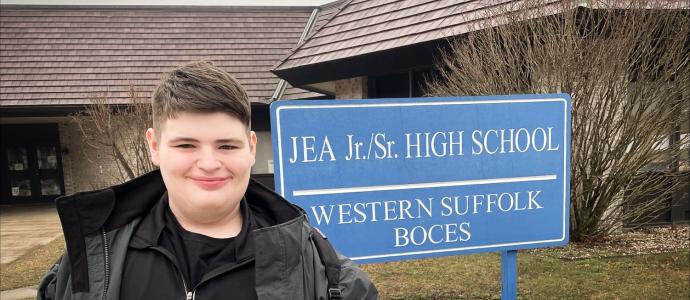 Luke stands outside his school in Long Island