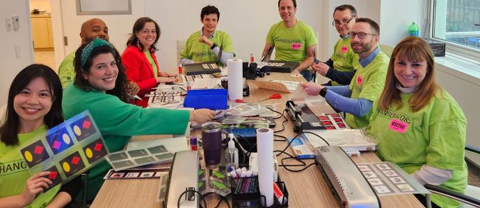 Group of people sat at a conference table with papers and laminating equipment.