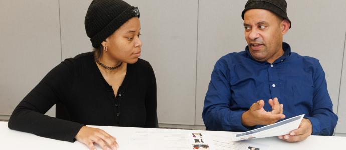 Woman and man sit side by side reviewing Easy Read papers.