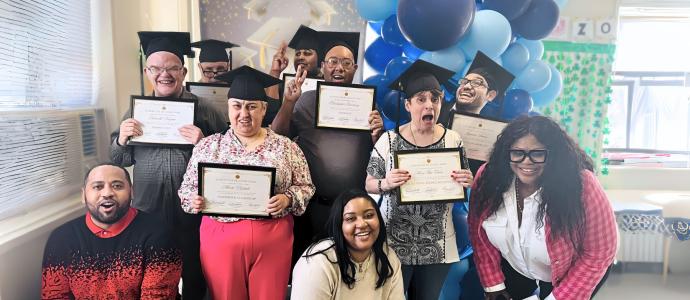 Group of people celebrating graduation from therapy, they are wearing mortars and holding certificates