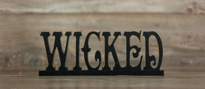 The word "WICKED" in a black fancy font on a wooden background