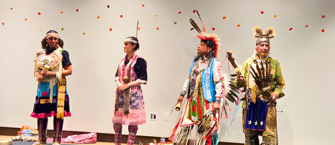 4 people in native America clothing dancing