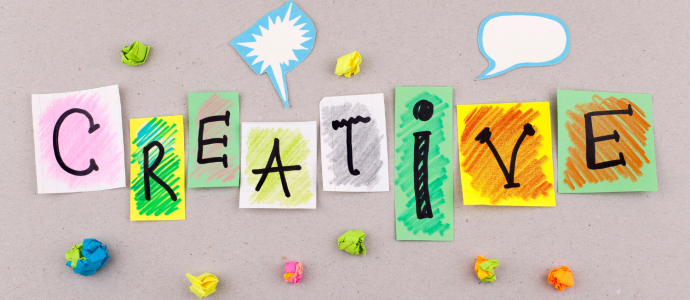 The work "creative" is spelled out on various style fonts on different papers with colorful additions around the word