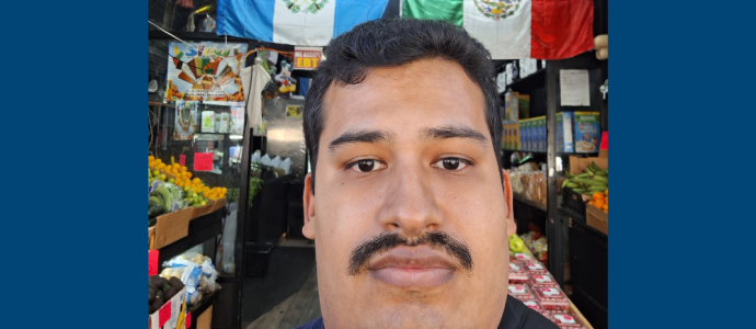 Orlando poses for a selfie in front of a store with Latin-American Flags