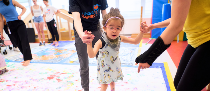 iHOPE student is supported by staff as they create a painting with their feet