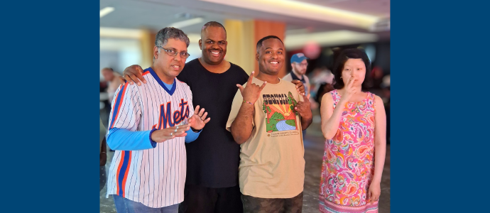 Kenneth with 3 other people standing together at the Summer Cookout Party, they are smiling and waving toward the camera