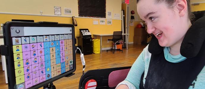 Amelia at her wheelchair, she is looking at the screen of the communication device she is using talk suite on