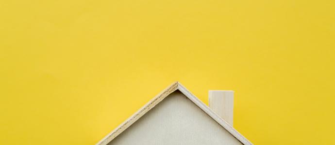 Miniature wooden house with yellow background