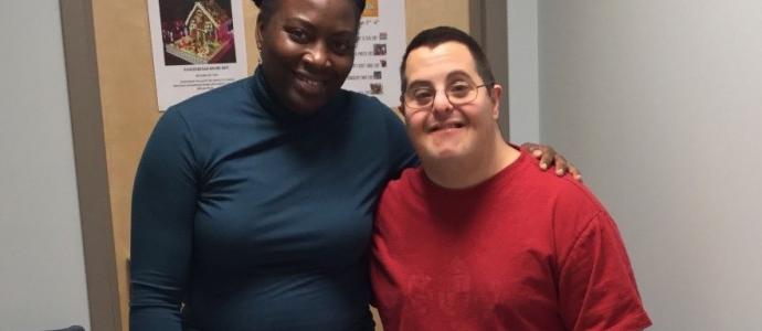 Two people stand in front of a door and pose/smile for picture